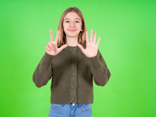 beautiful teen girl wearing green sweater showing and pointing up with fingers number eight while smiling confident and happy.
