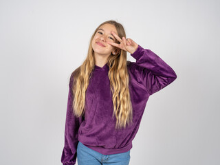 beautiful teen girl wearing purple sweater Doing peace symbol with fingers over face, smiling cheerful showing victory