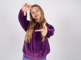 beautiful teen girl wearing purple sweater making finger frame with hands. Creativity and photography concept.