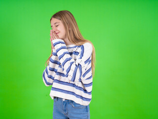 Overjoyed beautiful teen girl wearing striped sweater laughs joyfully and keeps palms pressed together hears something funny