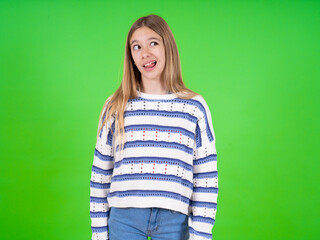 Funny beautiful teen girl wearing striped sweater makes grimace and crosses eyes plays fool has fun alone sticks out tongue.