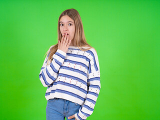 beautiful teen girl wearing striped sweater covers mouth and looks with wonder at camera, cannot believe unexpected rumors.