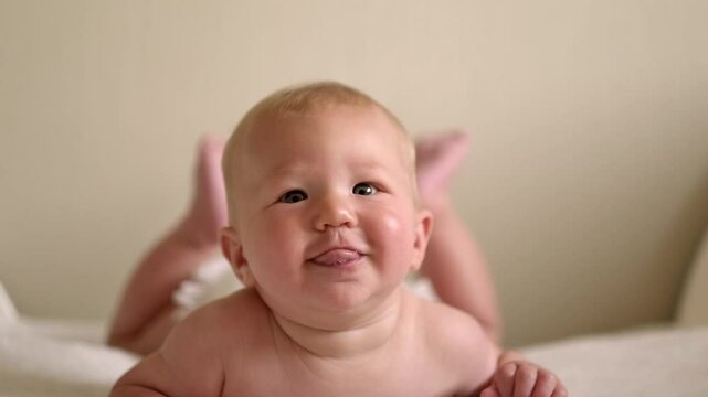 smiling infant baby lies on their tummy, looking up with bright eyes, Cild face expresses pure joy and curiosity, baby emotions, childhood happiness, home comfort