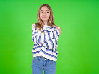 Charming pleased beautiful teen girl wearing striped sweater embraces own body, pleasantly feels comfortable poses. Tenderness and self esteem concept