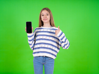 beautiful teen girl wearing striped sweater Show blank screen smartphone, thumb up recommend new app