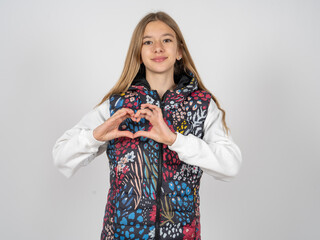 Serious beautiful teen girl wearing colorful vest keeps hands crossed stands in thoughtful pose...