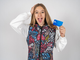 Impressed funny beautiful teen girl wearing colorful vest hand on head holding bank card