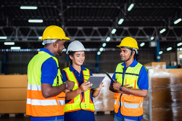 Workers collaborating in warehouse discussing project with tablet during daytime in industrial setting