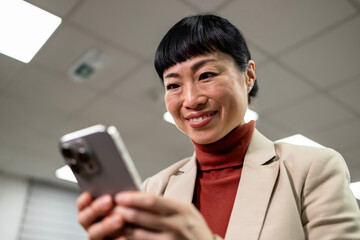 Close up view of beautiful Japanese businesswoman using her smart phone at work.