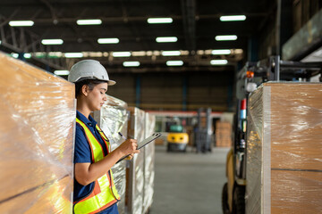 Worker conducts inventory check in warehouse with safety gear in bright industrial environment...