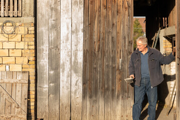 Farmer leaving old barn holding trowel at sunset © MexChriss