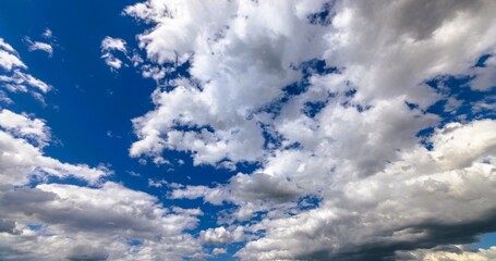 Blue sky with scattered white cumulus clouds .
