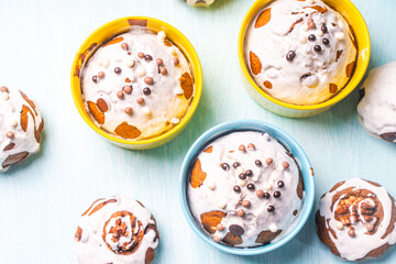 Cupcakes and muffins or Easter cakes poured with white icing on a light blue table. Space for text. View from above. Flat layout