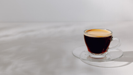 Cup of fresh espresso coffee on the white table with stylish sunlight shadows, copy space, aesthetic minimal style, banner size