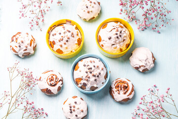 Cupcakes and muffins or Easter cakes poured with white icing on a light blue table. Space for text....