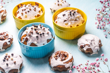 Cupcakes and muffins or Easter cakes poured with white icing on a light blue table. Space for text. View from above. Flat layout