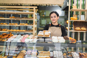 Pastry chef arranging delicious pastries in bakery display case