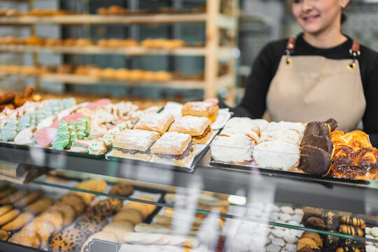 Pastry chef arranging delicious pastries in bakery display case