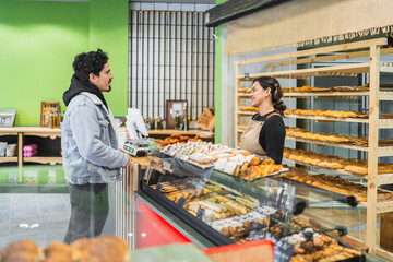 Customer ordering pastries from baker in bakery shop