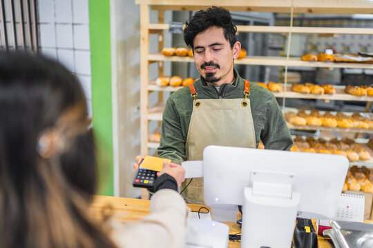 Baker accepting contactless payment from customer in bakery shop - Powered by Adobe
