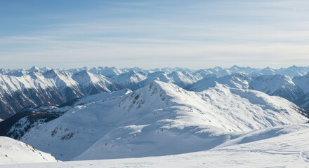Panoramic view of snow-covered mountain range under a clear blue sky on a bright winter day.