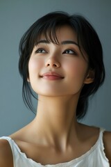Fototapeta premium A woman with a black hair and a white tank top is smiling