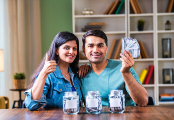 Indian couple placing cash in labeled jars, symbolizing smart budgeting and investment strategies