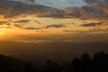 Autumn sunset light with clouds in blue sky with mountain landscape between the trees in horizontal HDR