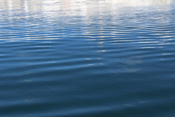 Ripples on blue water surface texture. Water with reflection background. Sea surface with small waves.