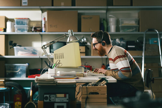Cheerful nerd guy using an old computer