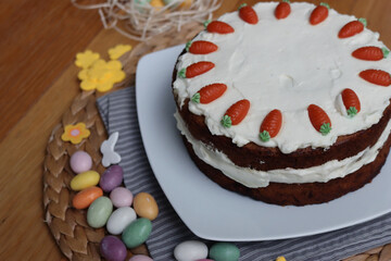 Homemade carrot cake with mascarpone cream cheese icing and mini marzipan carrot decorations with Easter eggs and decorations