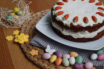 Homemade carrot cake with mascarpone cream cheese icing and mini marzipan carrot decorations with Easter eggs and decorations