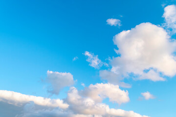 Blue sky background with white clouds and silhouette of flying airplane