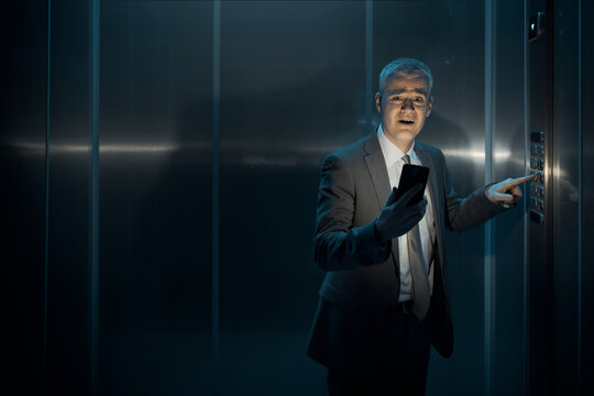 Worried man stuck in the elevator and pressing the emergency button