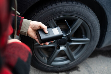 man driver hand inflating tires of vehicle, removing tire valve nitrogen cap for checking air...