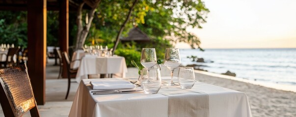 Elegant Beachfront Dining Setup with Glassware, Table Linens and Natural Surroundings at Sunset