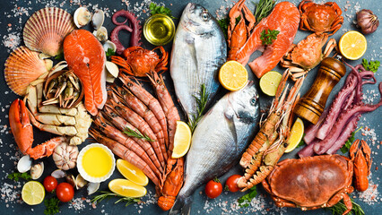 Fresh Seafood Background. Assortment of seafood: Fresh fish, shrimp, oysters, lobster and octopus on slate black table. Top view.
