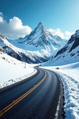Asphalt ribbon winding through a pristine, snow-covered mountain pass under a vibrant blue sky