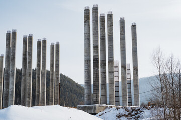 Tall concrete pillars majestically rise on a snowcovered hill, creating a striking contrast with the peaceful winter landscape, significantly enhancing their visual impact and allure