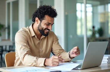 Fototapeta premium Successful young businessman checking documents, accounts. Happy smiling man with laptop inside office. Confident hispanic financier is satisfied with achieved results, career, reviewing paperwork.