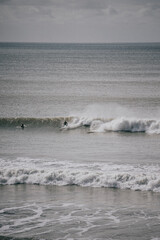 A man is surfing on a wave in the ocean. The water is calm and the sky is cloudy