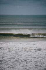 The ocean is calm and the waves are small. The sky is cloudy and the water is a light blue color