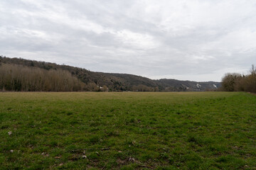 Obraz premium Expansive green meadows of La Roche-Guyon under a moody sky inviting exploration and tranquility