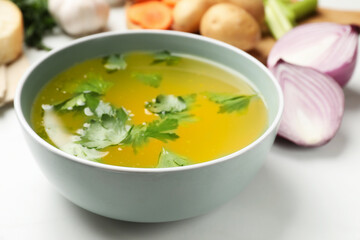Tasty chicken bouillon in bowl on white table, closeup
