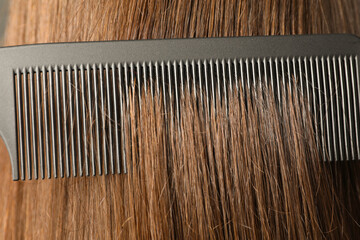 Brushing hair with plastic comb, closeup view
