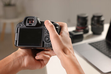 Photographer with professional camera at white desk indoors, closeup