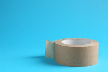 Roll of masking tape on light blue background, space for text