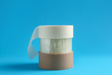 Rolls of different adhesive tapes on light blue background