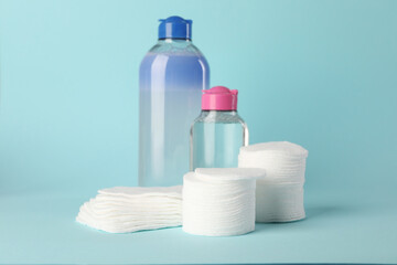Clean cotton pads and micellar water on light blue background