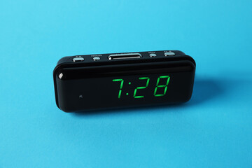 Digital alarm clock showing 7:28 o'clock on light blue background